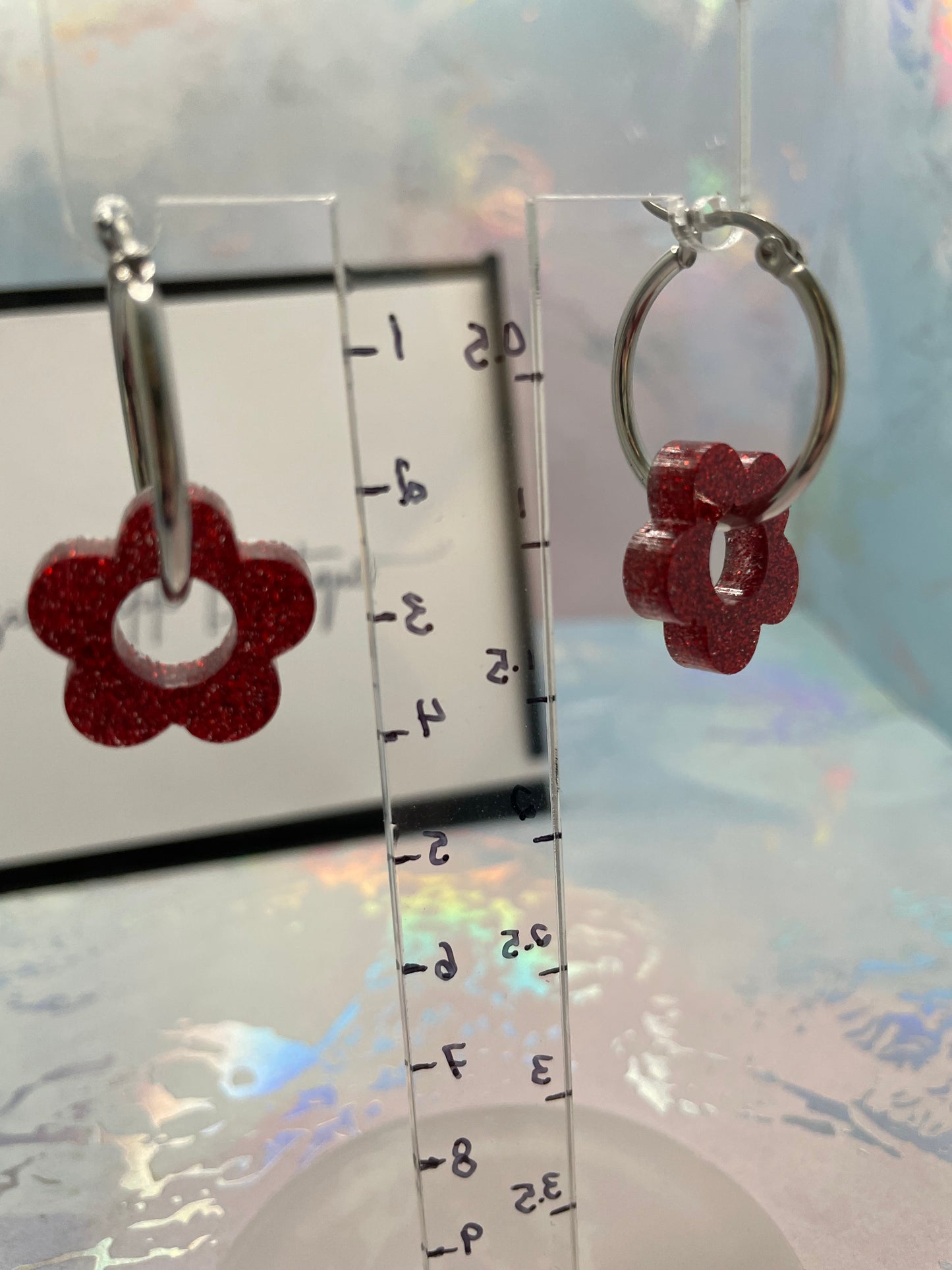 Red flower-shaped keychains on a clear ruler against a light background