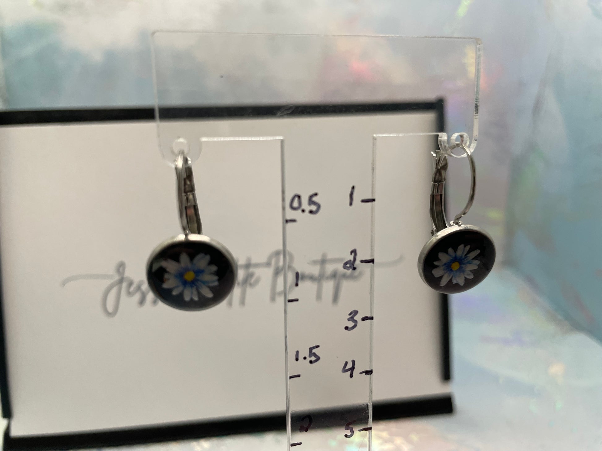 Pair of earrings on a clear stand with measurement scale