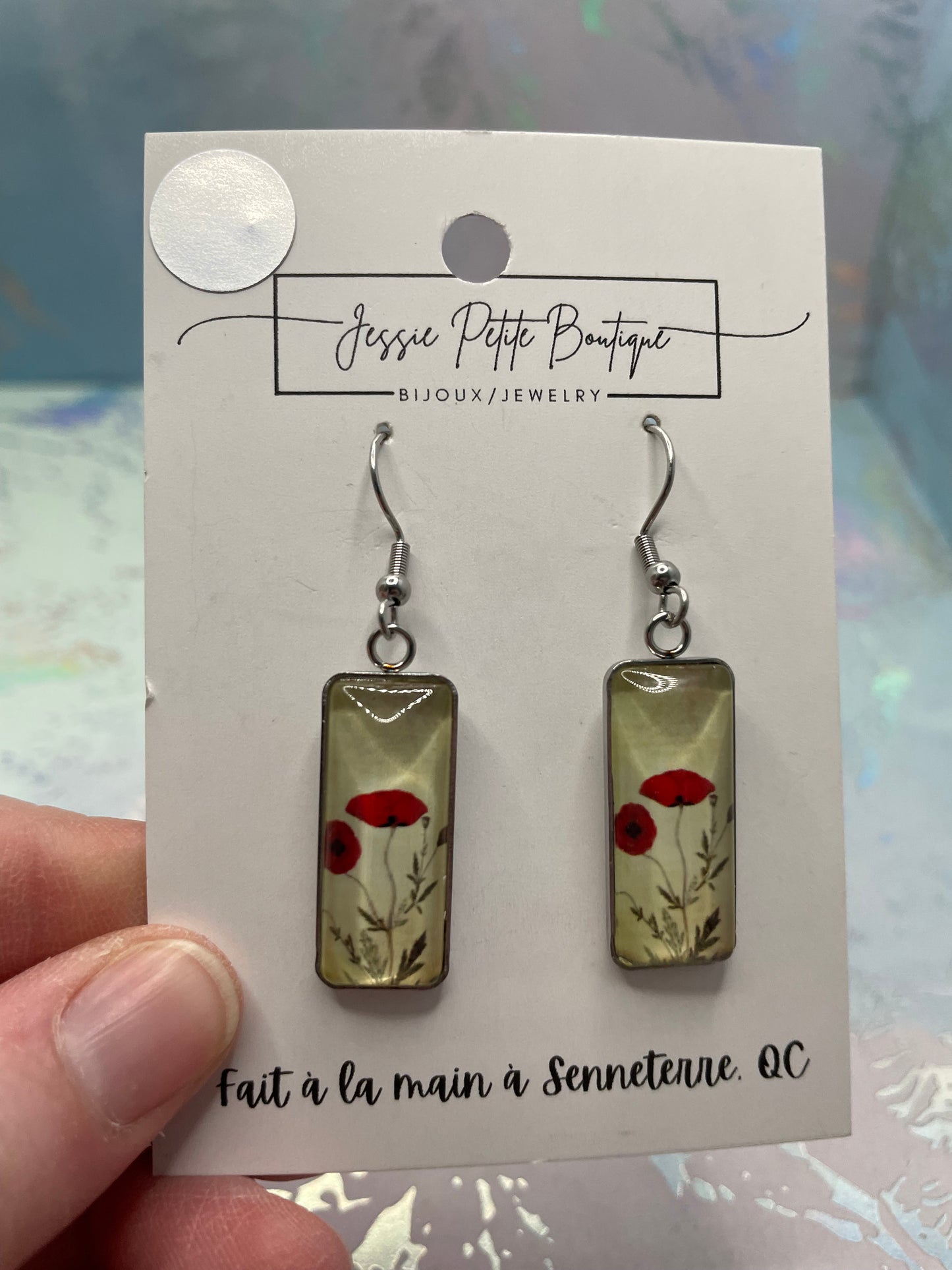 Pair of earrings on a card held by a hand with a blurred background