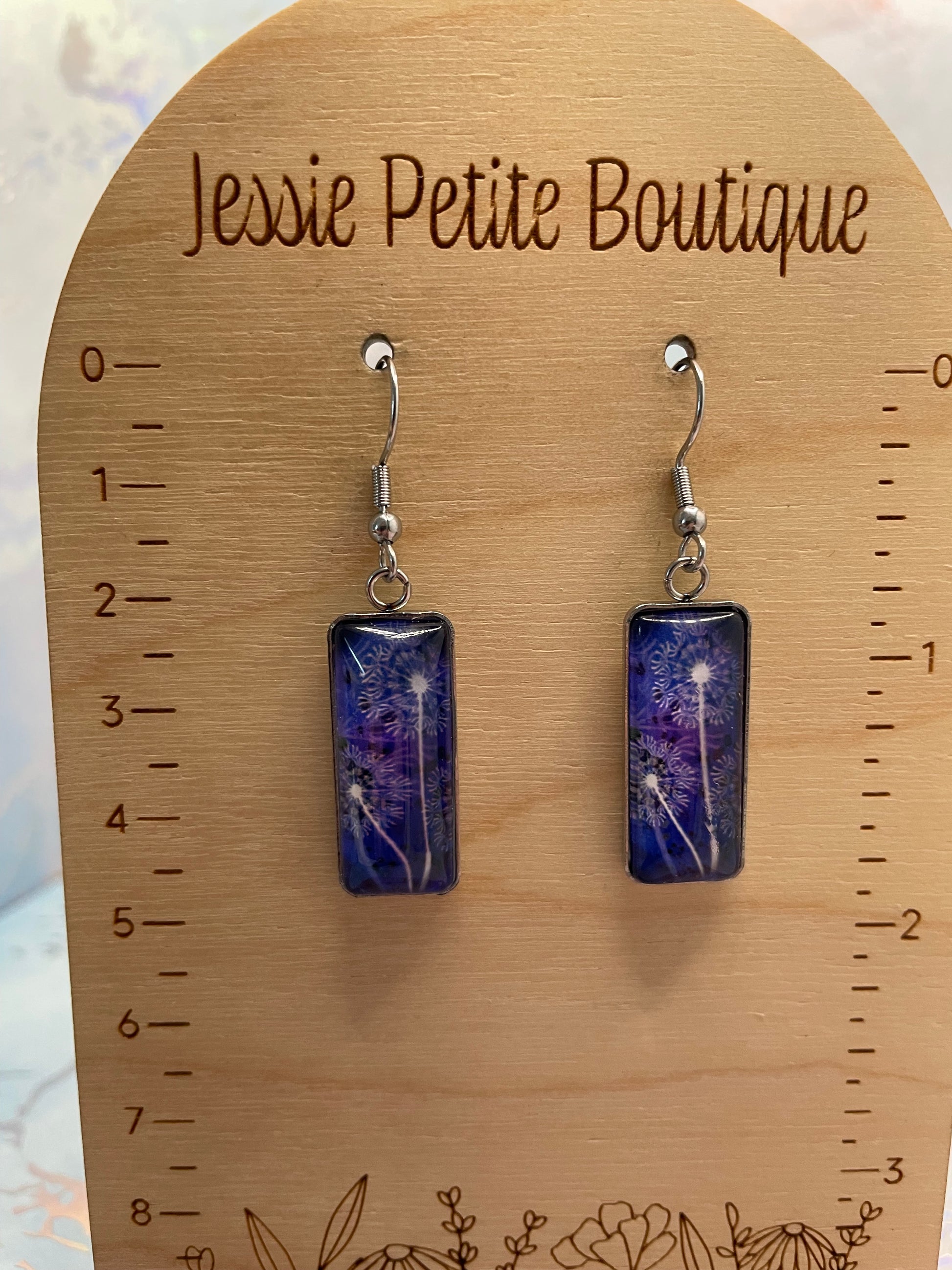 Pair of purple rectangular earrings on a wooden card with 'Jessie Petite Boutique' branding.
