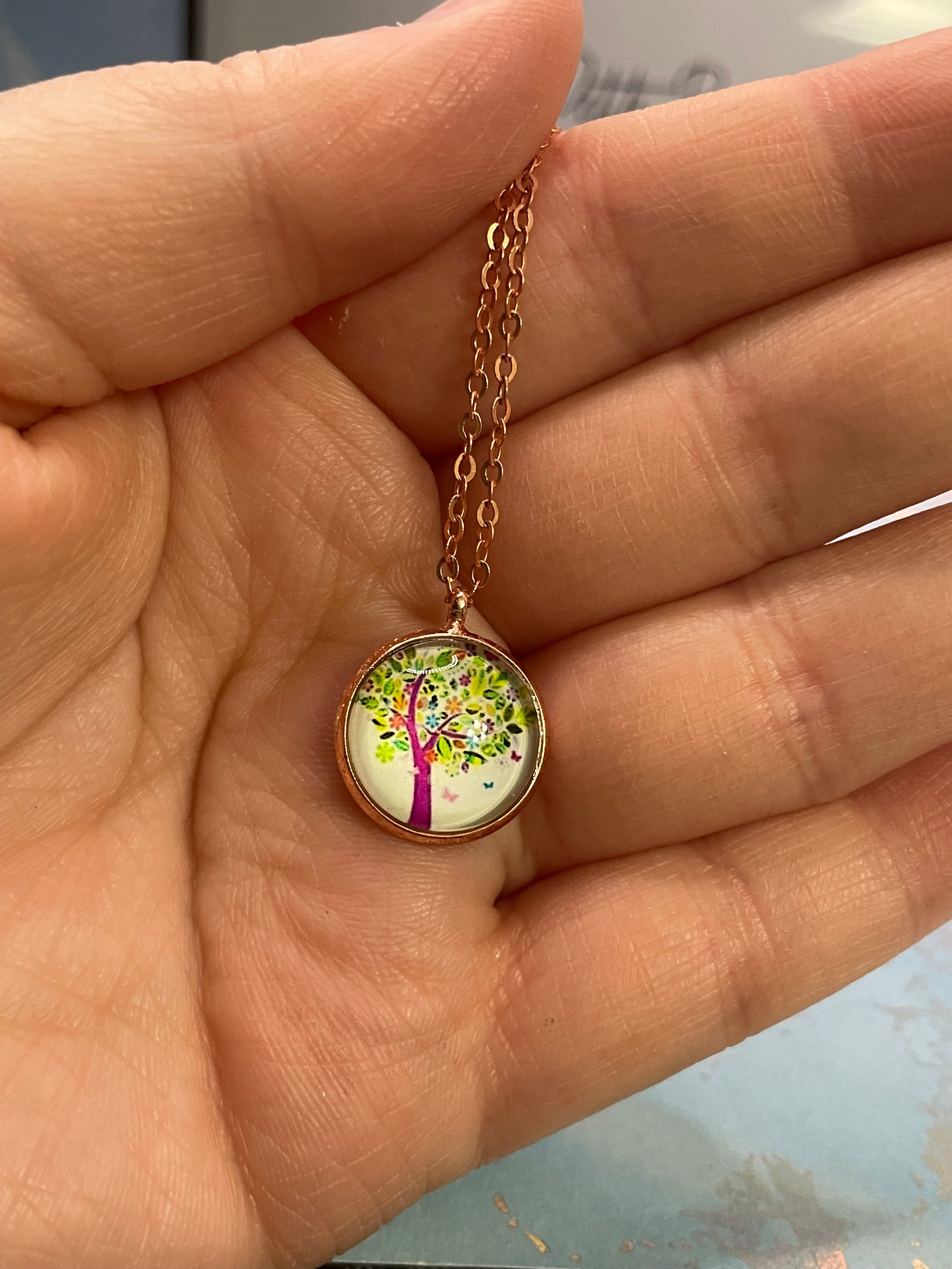 Necklace with a round pendant featuring a colorful design held in a hand.