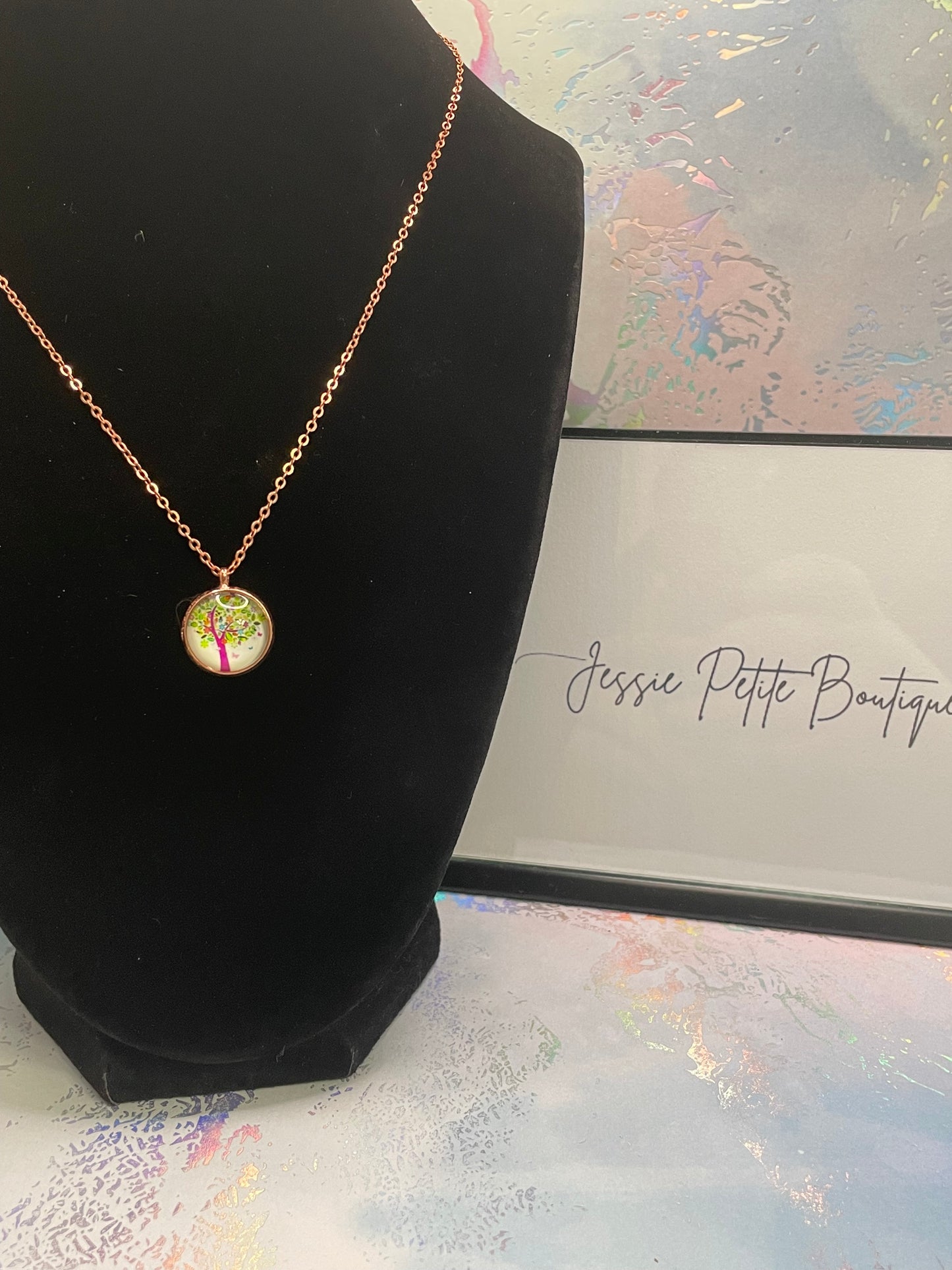 Colourful Tree Design Necklace on a black stand against a decorative background