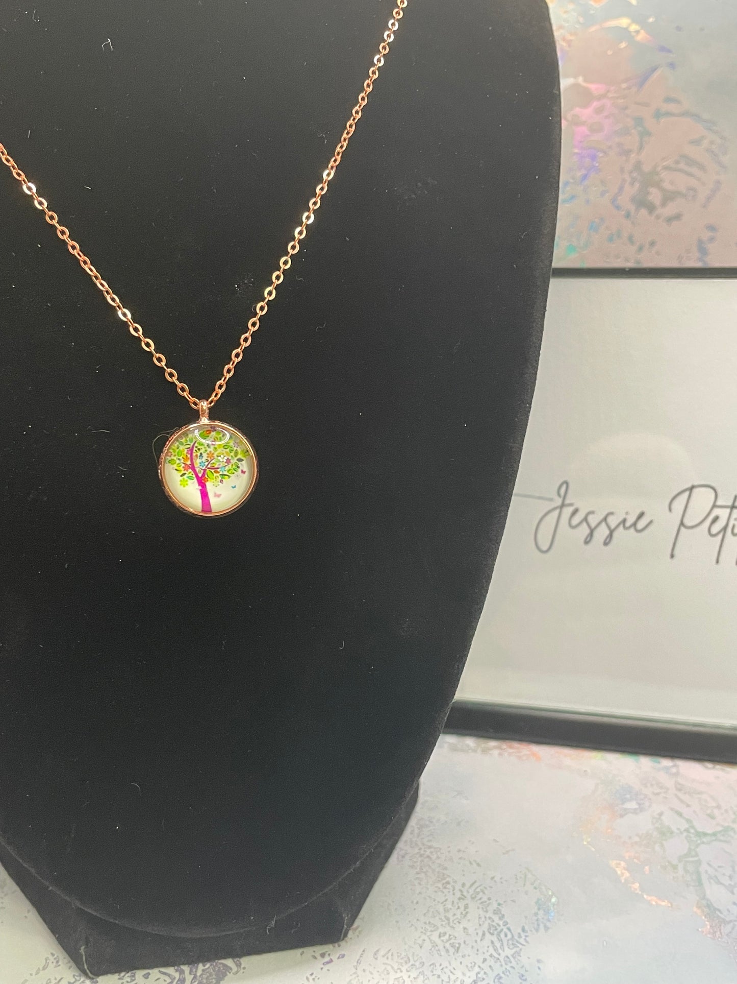 Necklace with a round pendant on a black mannequin torso, with 'Jessie Petite Boutique' branding in the background.