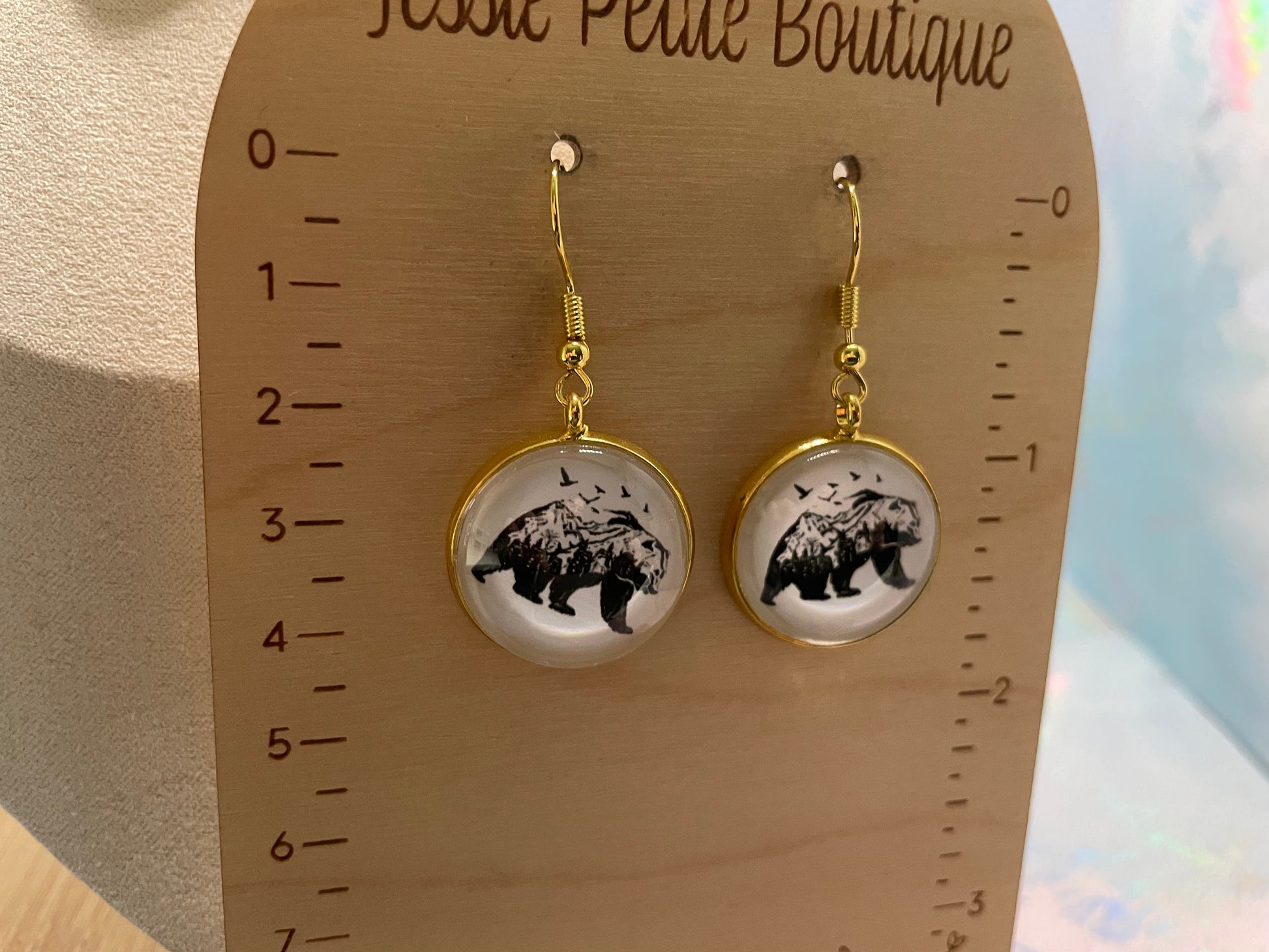 Pair of earrings with bear design on a wooden display card.