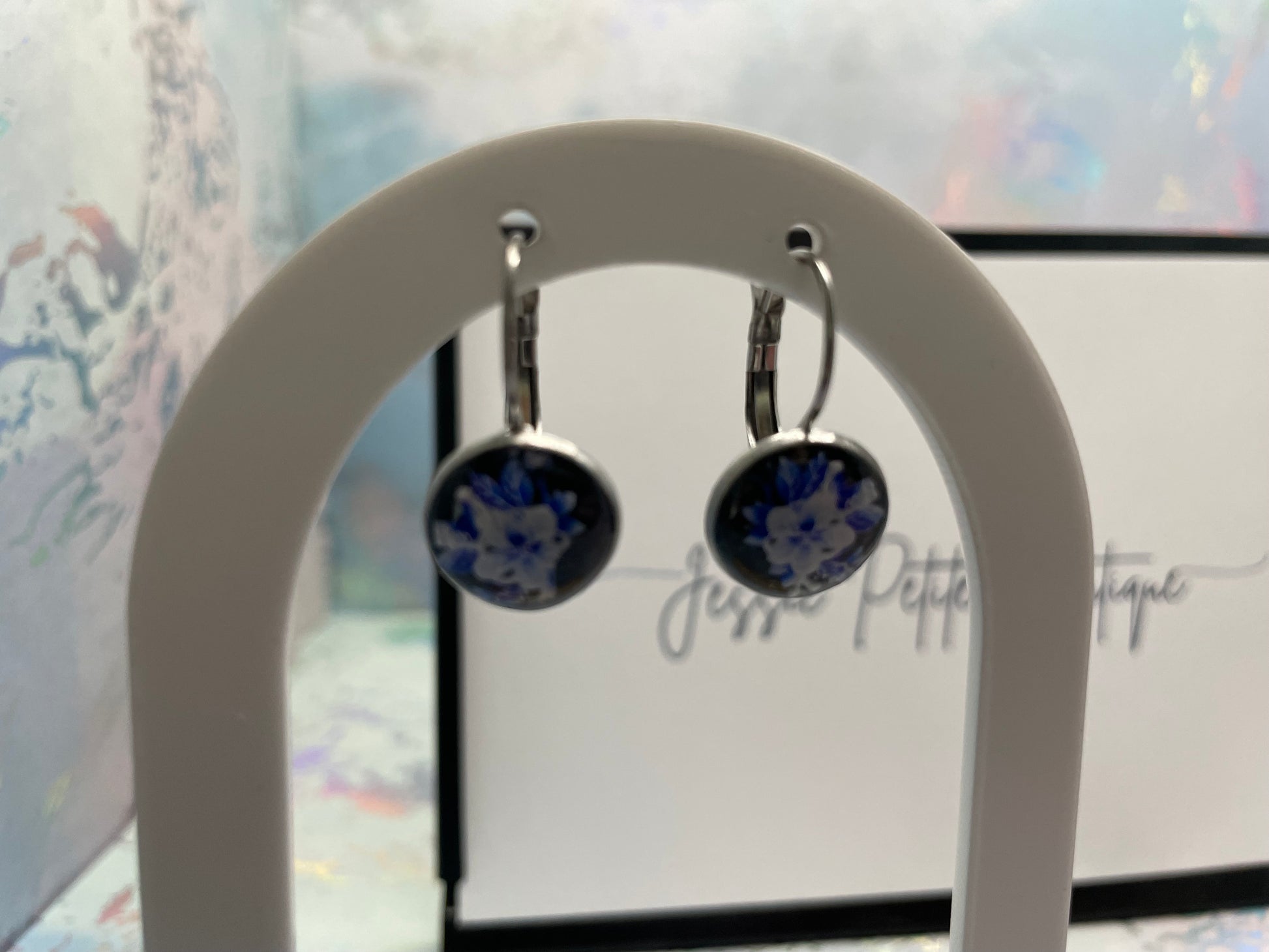 Pair of earrings on a white stand with a blurred background