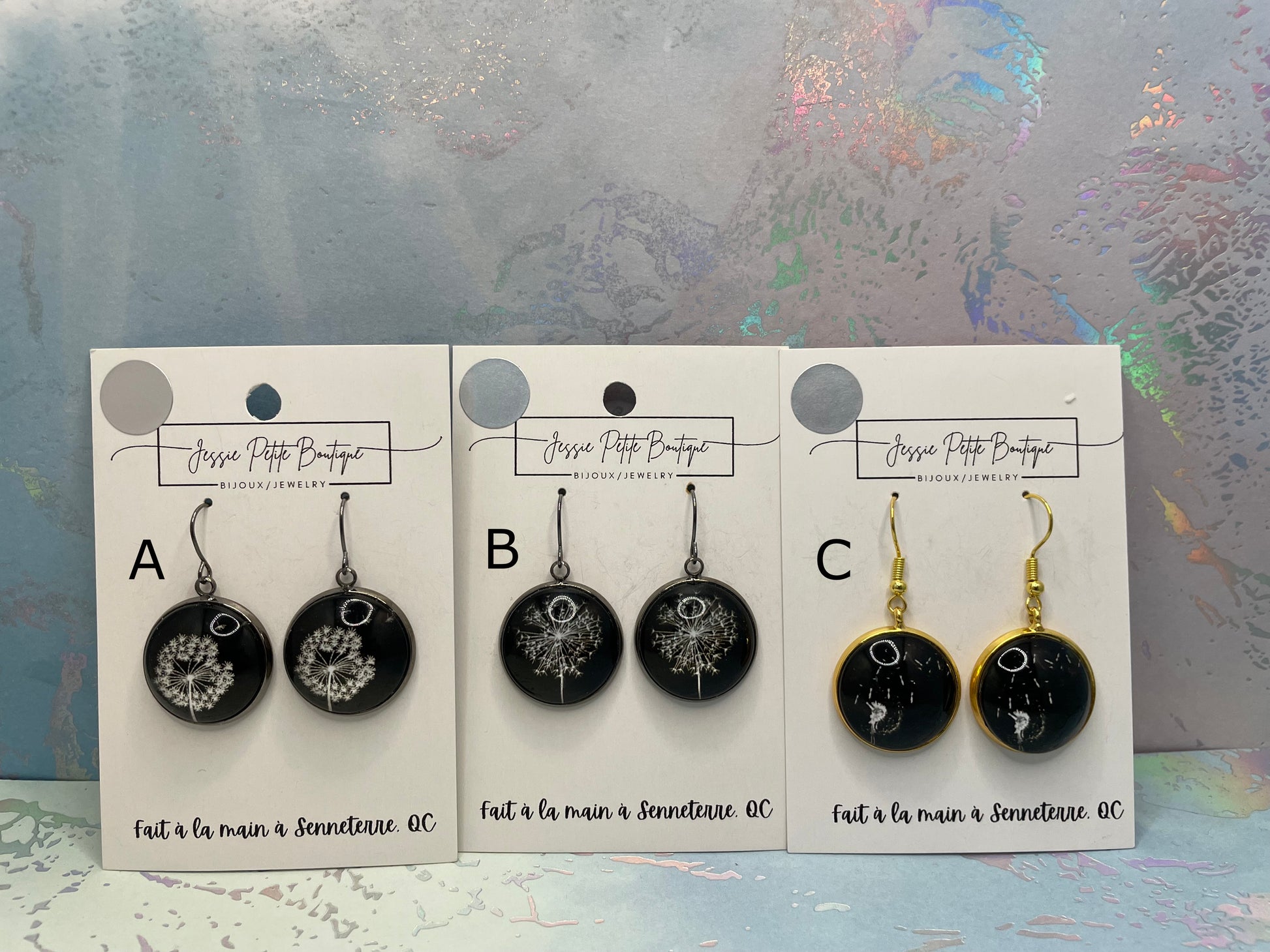 Three pairs of earrings on display cards with a decorative background