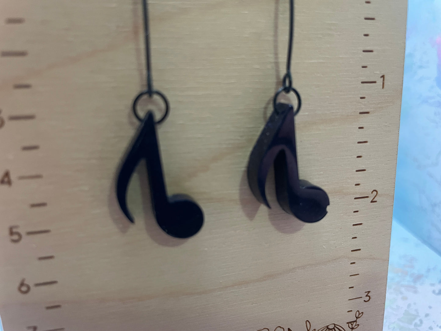 Dark Blue earrings shaped like music notes on a wooden surface with a ruler for scale.