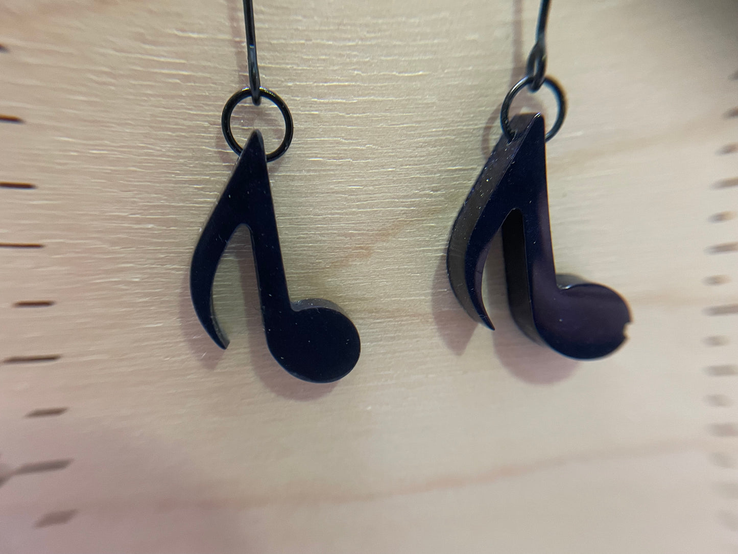 Dark Blue music note earrings on a light wood background