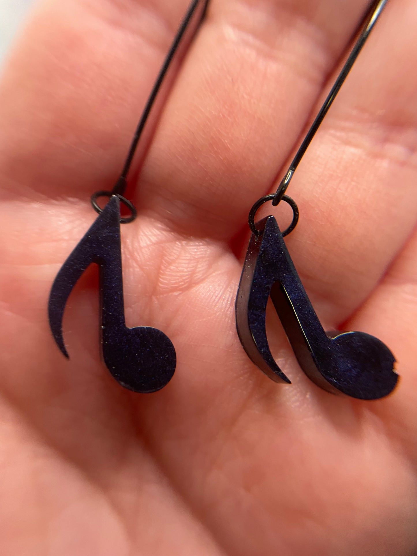 Close-up of a hand holding two Dark Blue Music Note Earrings