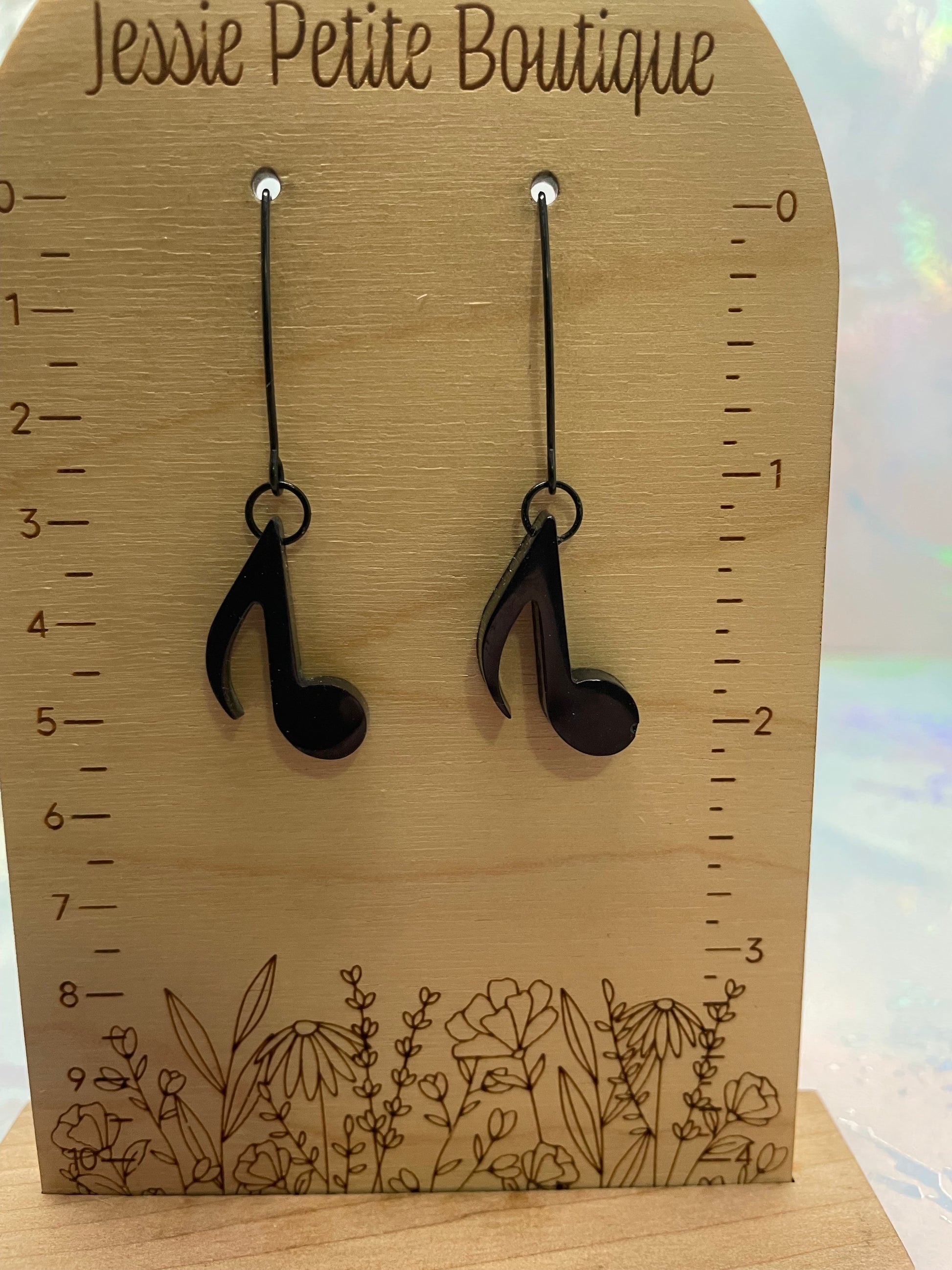 Wooden measuring board with floral design and two black music note earrings 