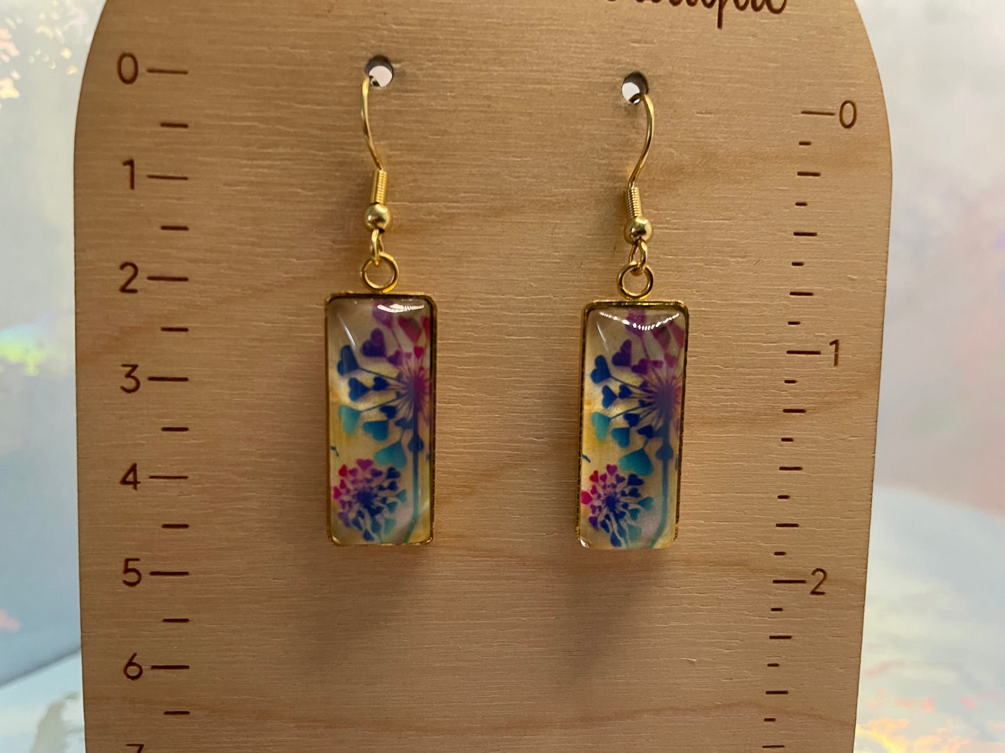 Pair of floral earrings on a wooden ruler for scale.