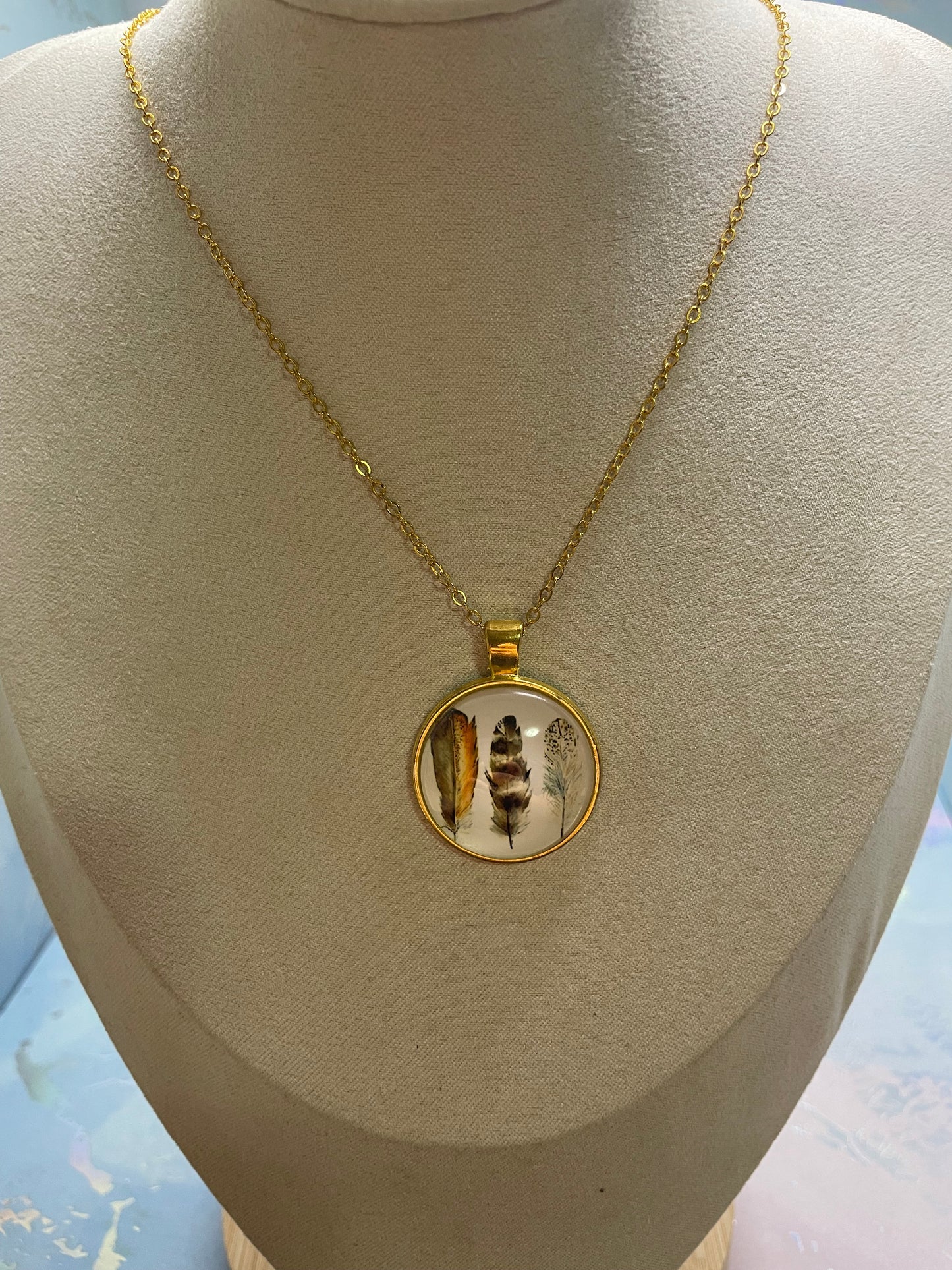 Collier cabochon doré rond à trois plumes