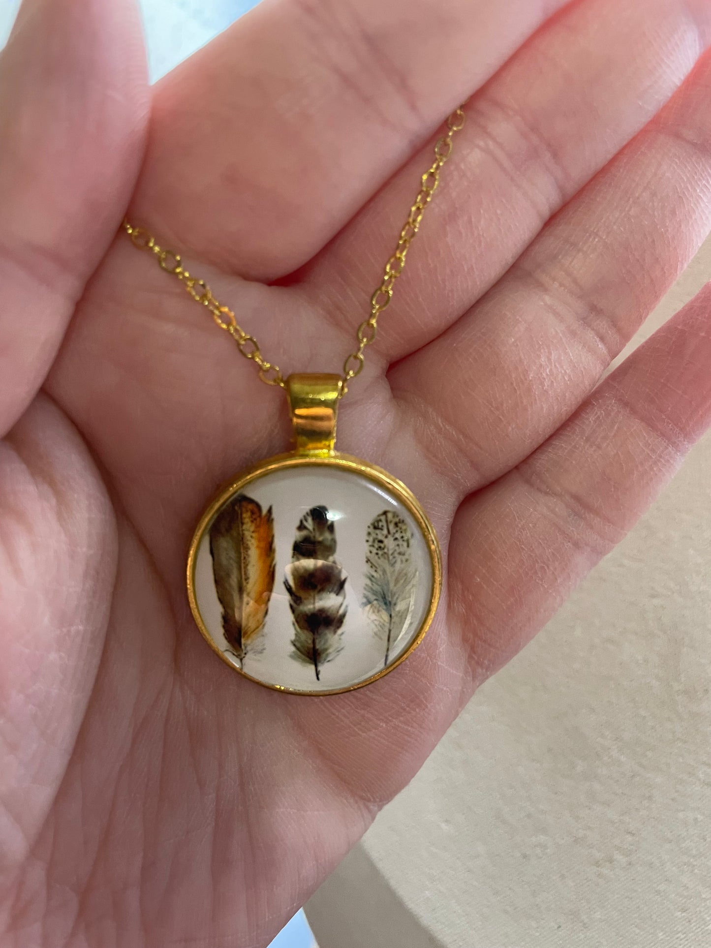 Collier cabochon doré rond à trois plumes