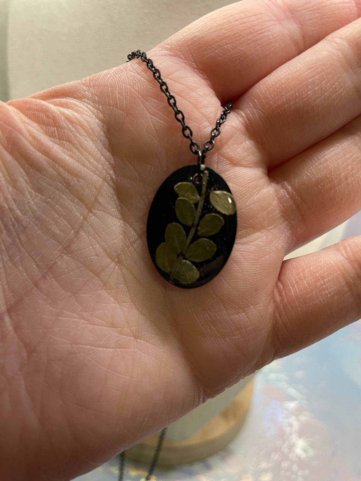 Collier ovale en résine noire avec feuillage