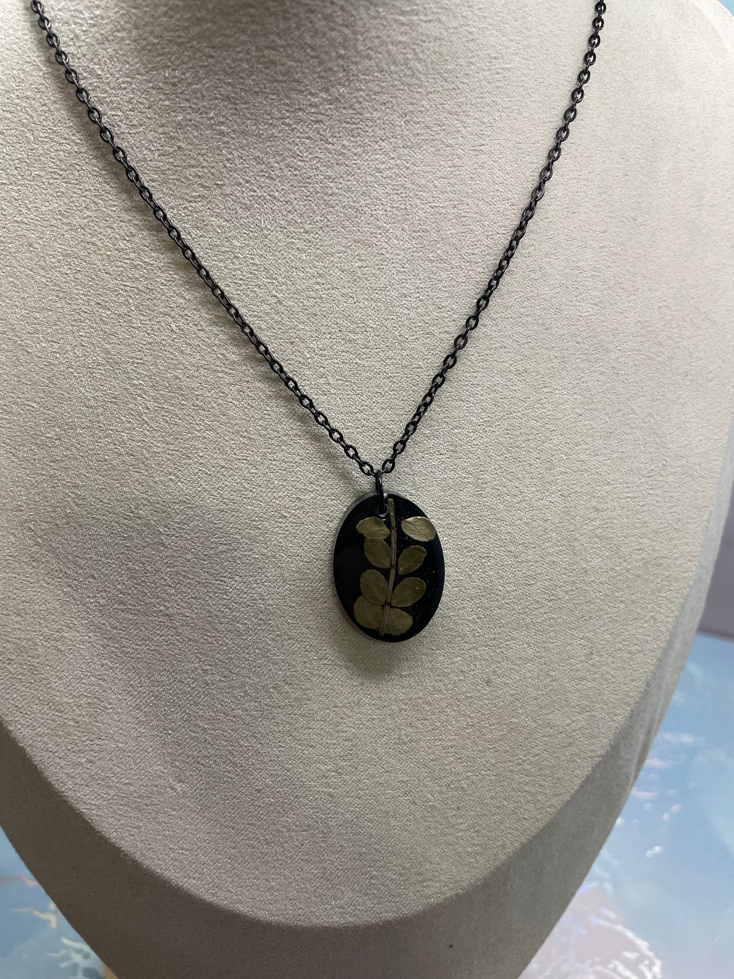 Collier ovale en résine noire avec feuillage