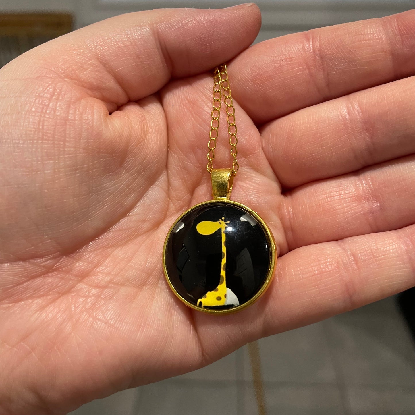 Collier giraffe dans un cabochon dorée