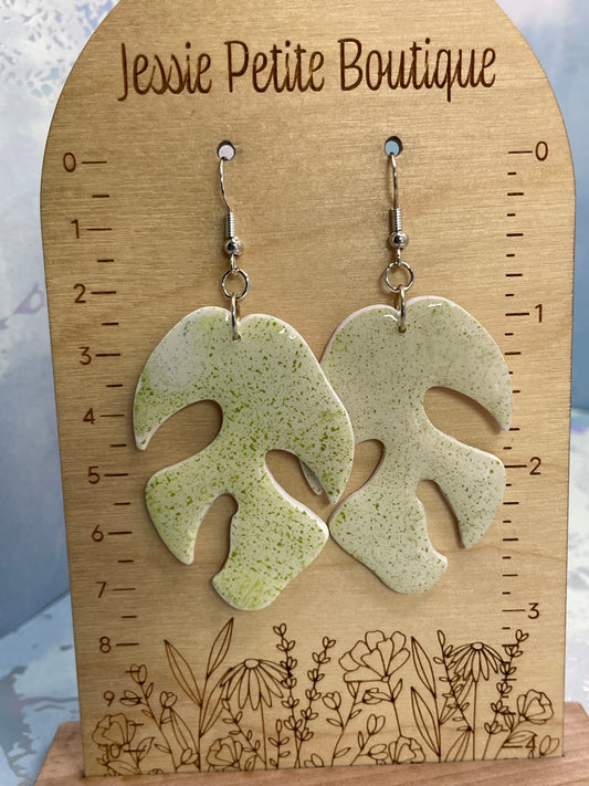 "Speckled sage monstera leaf earrings on white background showing botanical silhouette"