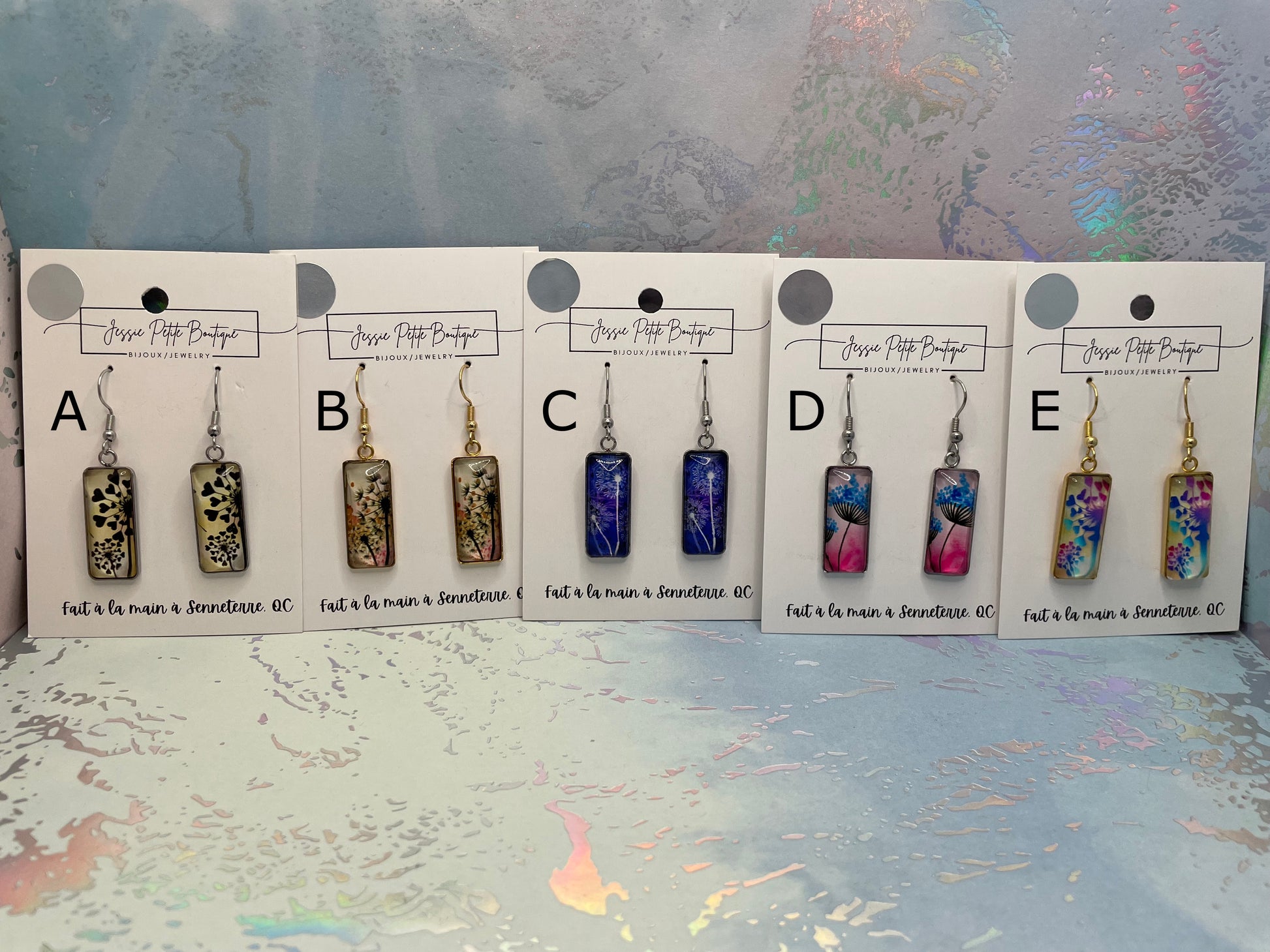 Set of earrings on display with labels on a textured surface
