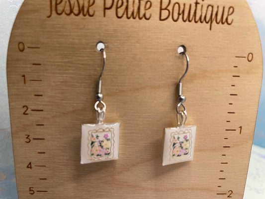 Pair of earrings with floral design on a wooden ruler, featuring 'Jesse Paley Boutique' branding.