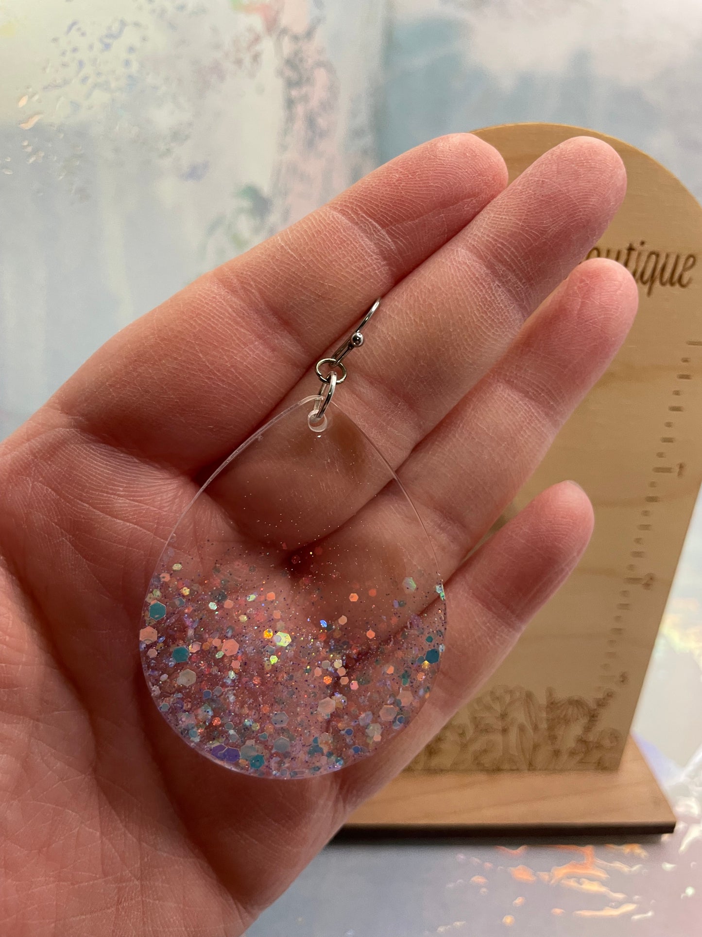 Hand holding a big-sparkly teardrop earrings with a blurred background