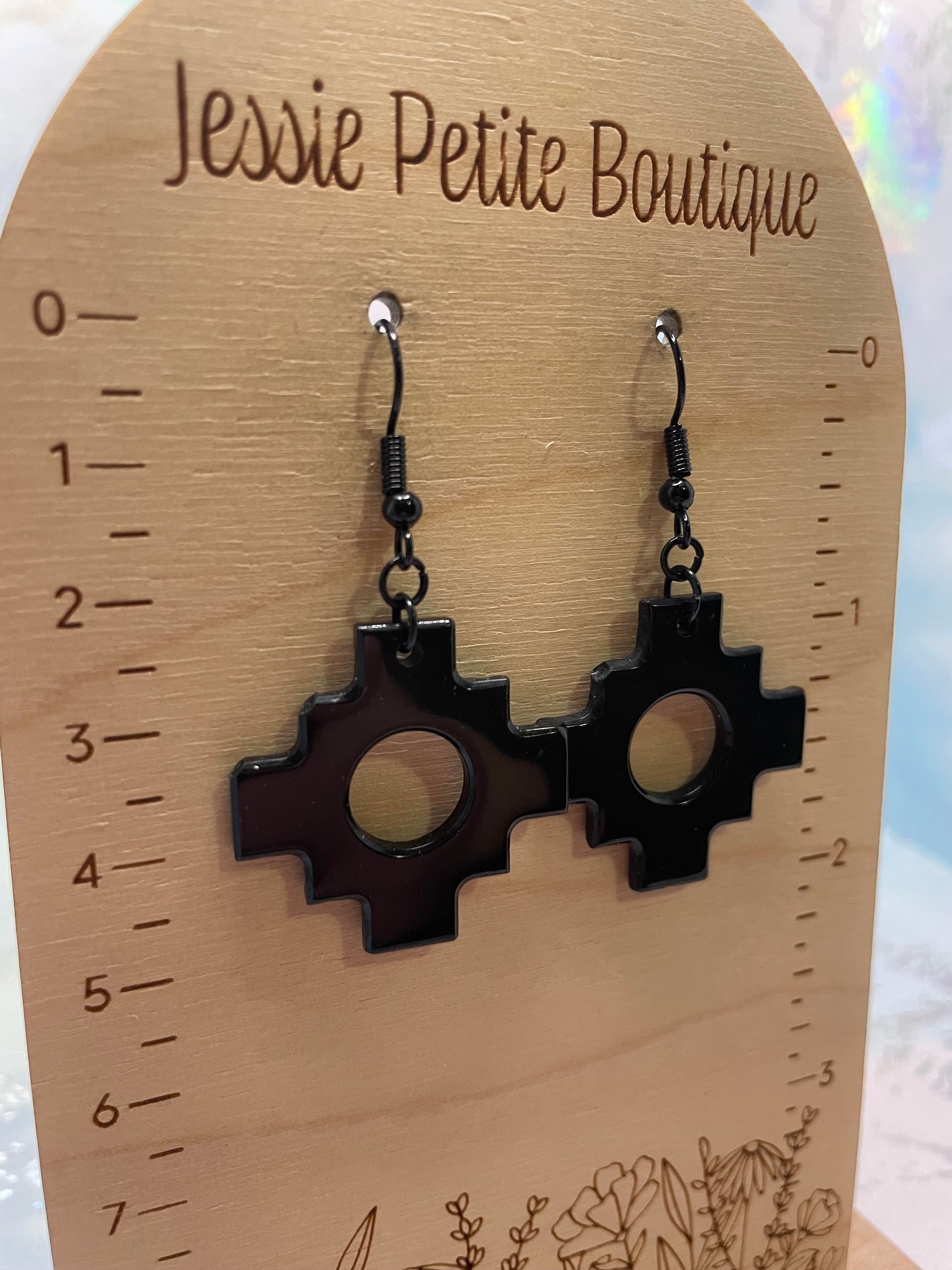 Black earrings on a wooden tag with measurements, branded 'Jessie Petite Boutique'.