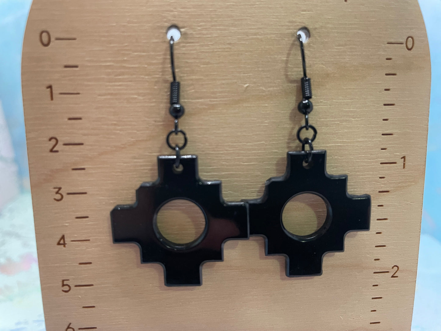 Black earrings on a wooden stand with measurement scale