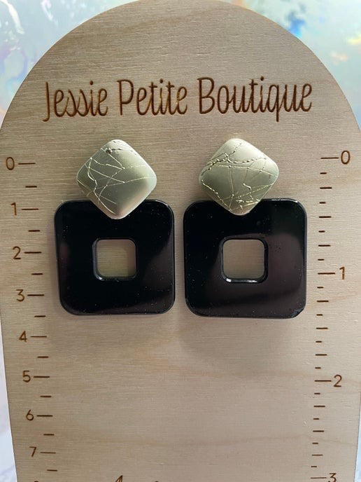 Pair of earrings on a wooden measuring board with 'Jessie Petite Boutique' branding.