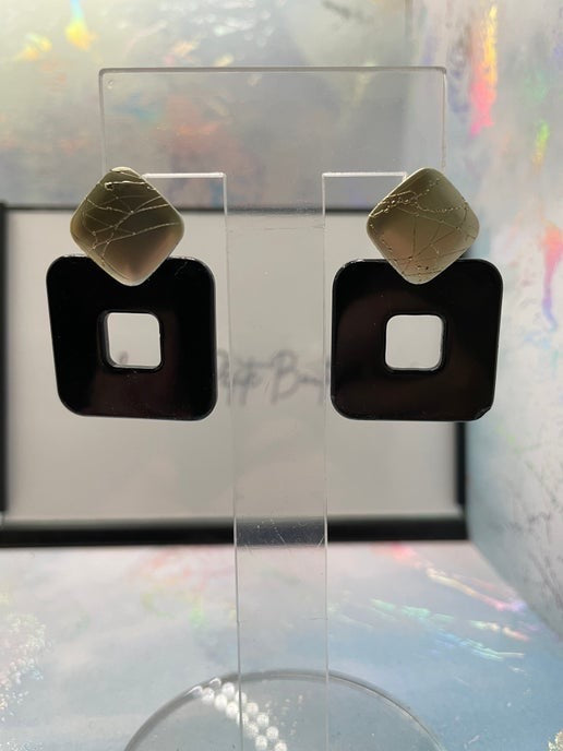 Pair of earrings on a clear stand with a colorful background