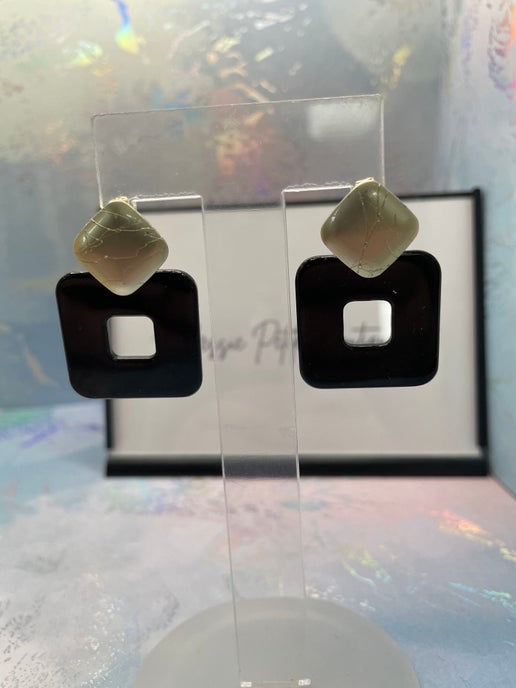 Pair of earrings on a clear stand with a colorful background