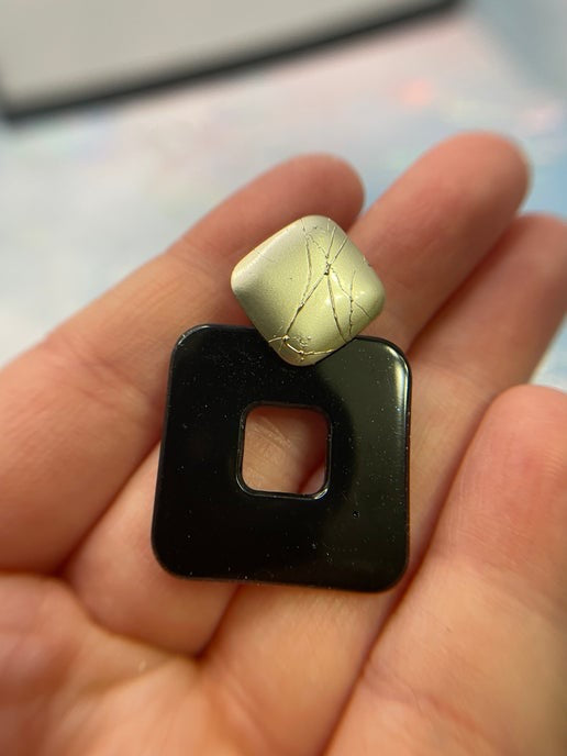 Black square object with a gold cube on top held in a hand