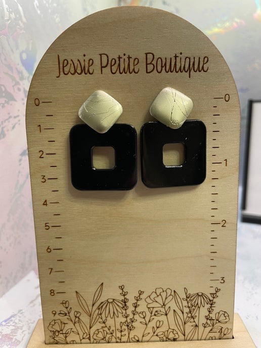 Pair of earrings on a wooden stand with 'Jessie Petite Boutique' branding.