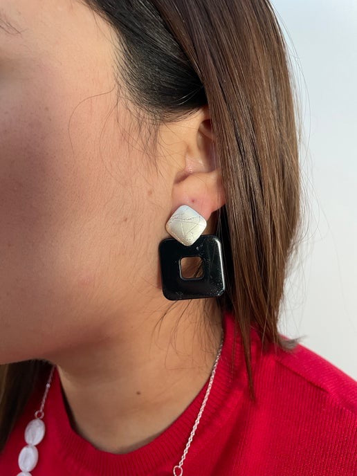 Close-up of a person wearing a black and gold earring with a red garment.