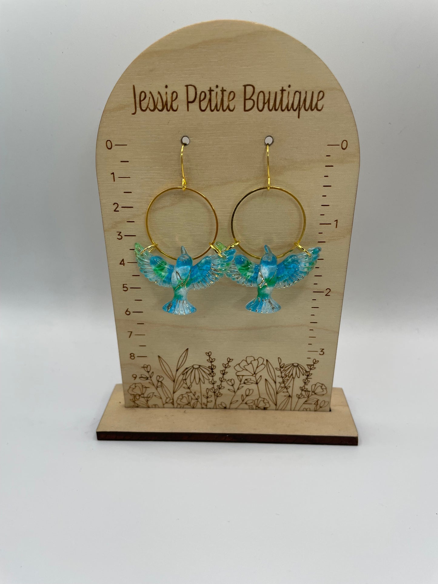 Jewelry display card with bird earrings on a plain background