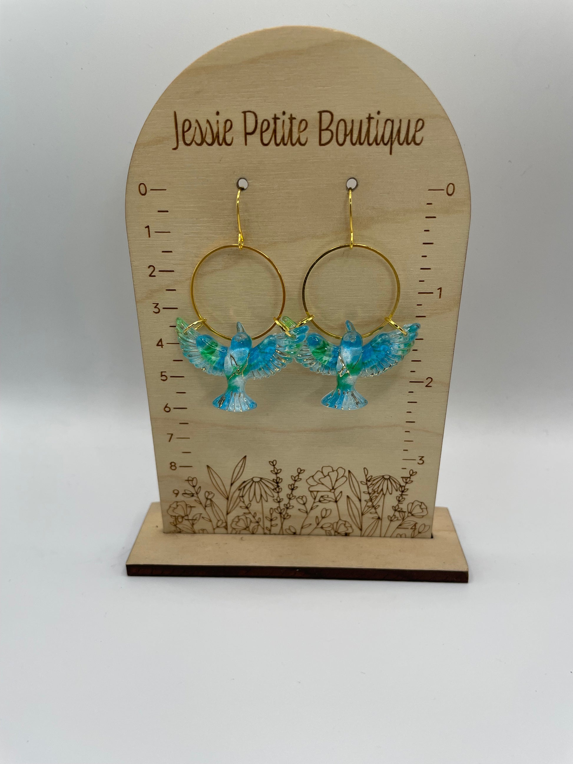 Jewelry display card with bird earrings on a plain background