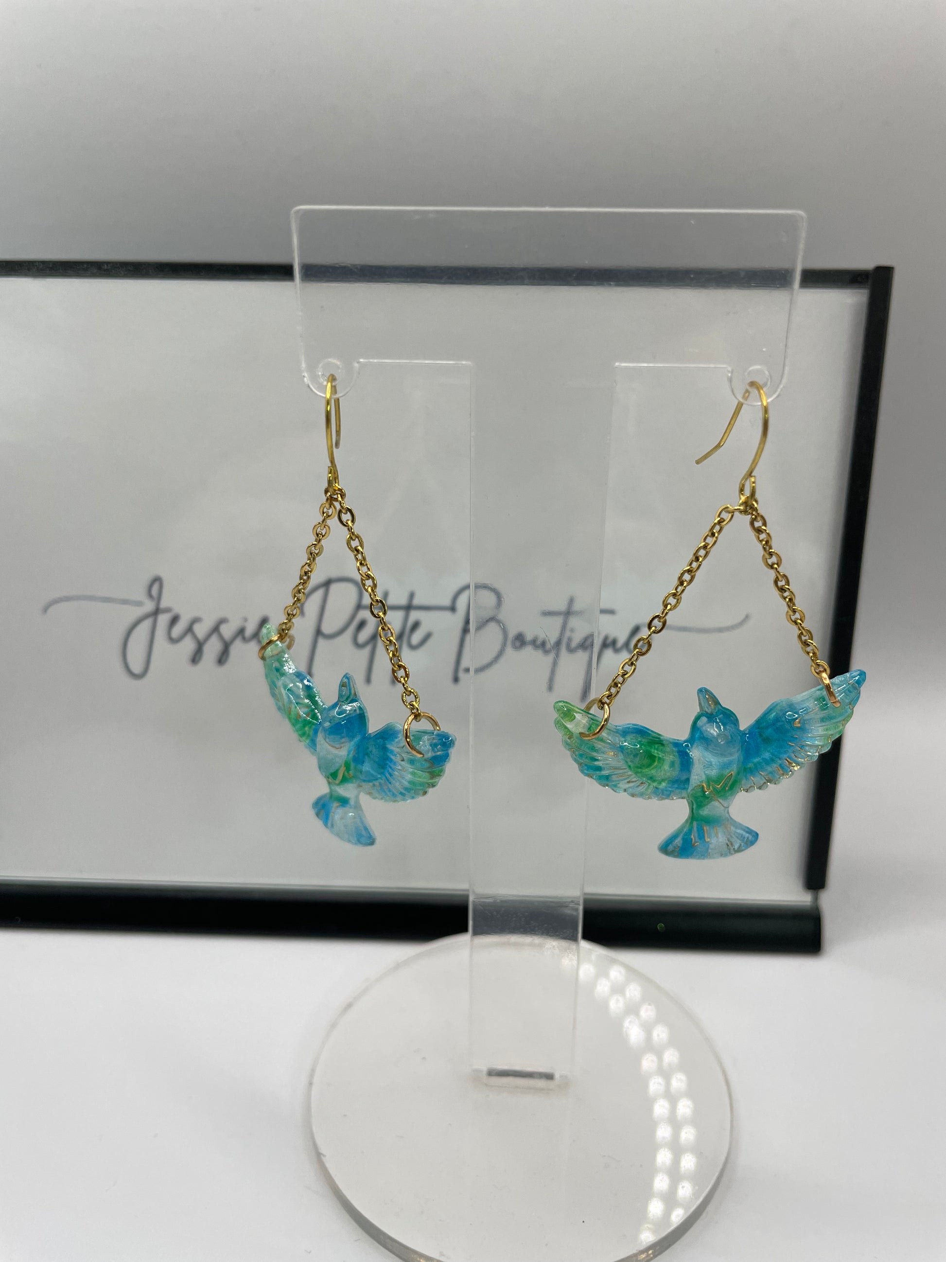 Blue butterfly earrings on a branded card with a light reflection.