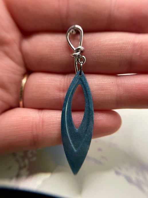 Blue teardrop-shaped pendant on a hand
