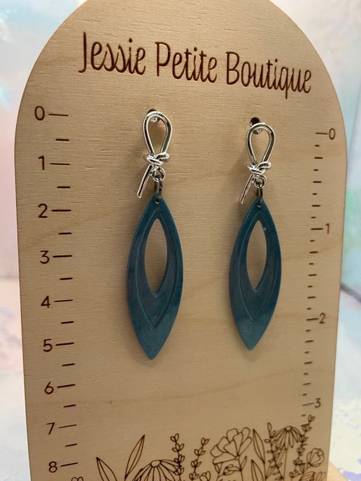 blue earrings on a wooden measuring scale with 'Jessie Petite Boutique' branding.