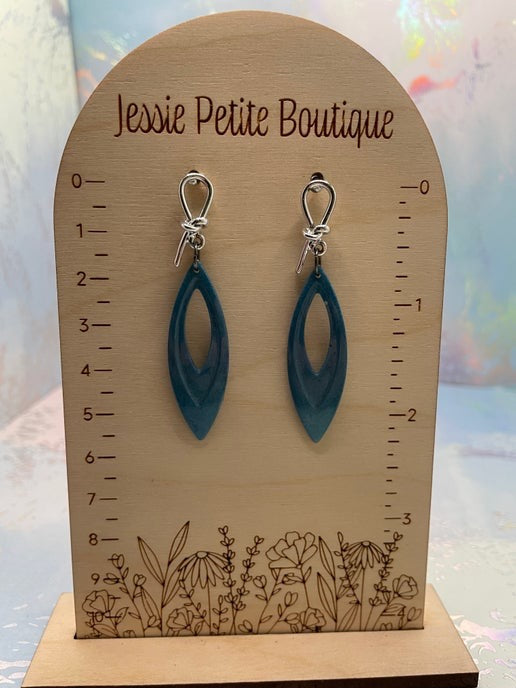 Blue earrings on a wooden display stand with 'Jessie Petite Boutique' branding.