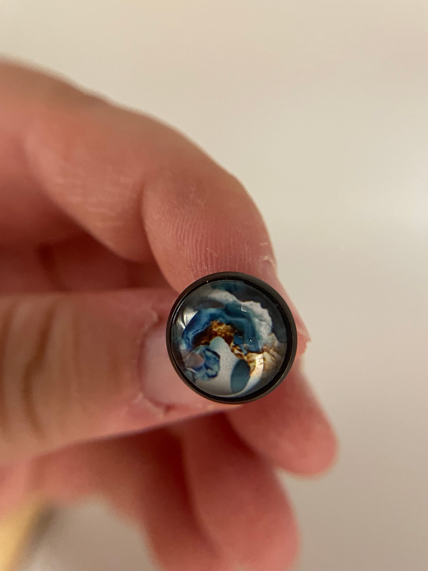 Close-up of a hand holding a stud with a blue and gold interior.