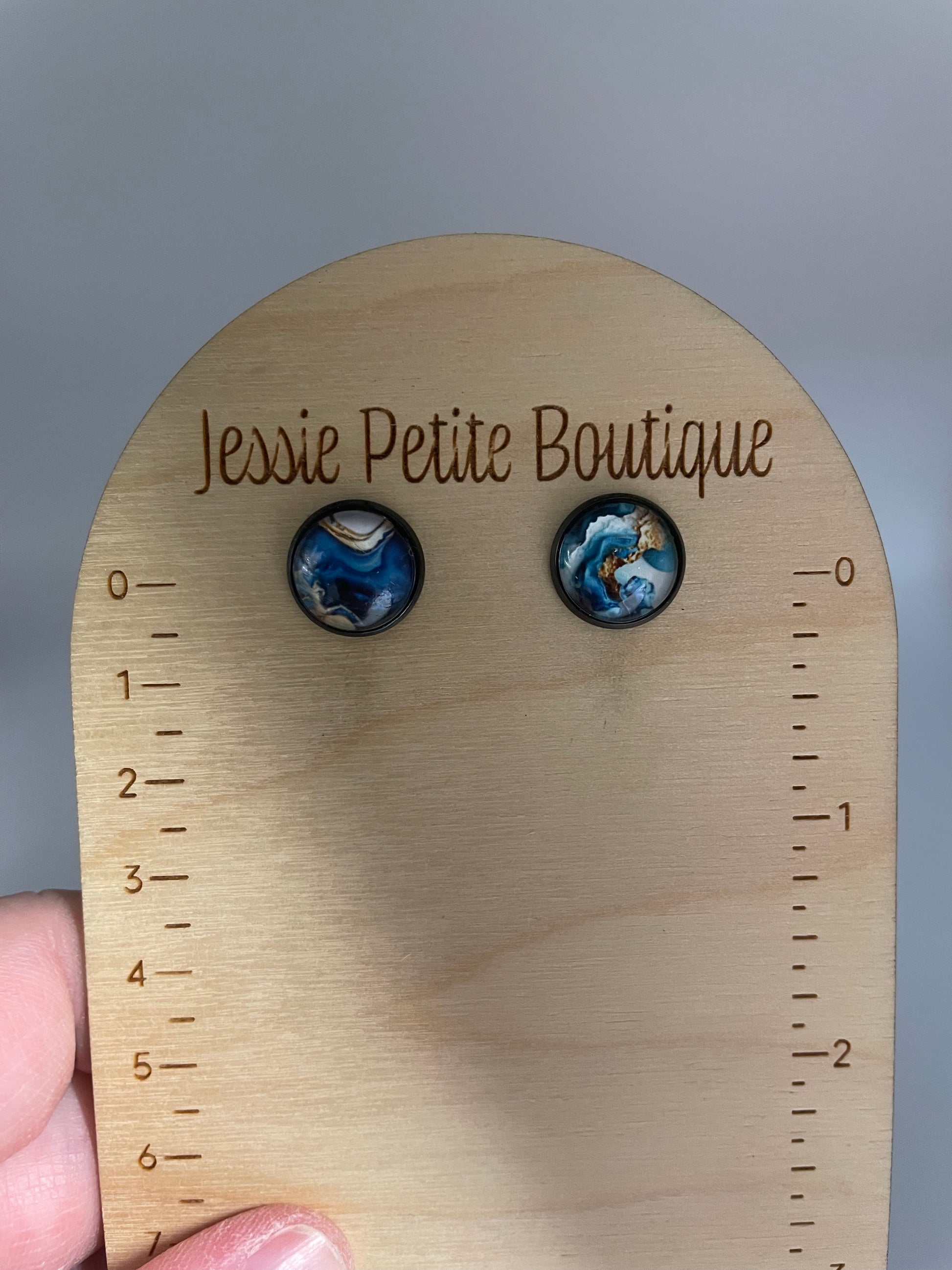 Pair of earrings on a wooden display card with 'Jessie Petite Boutique' branding.
