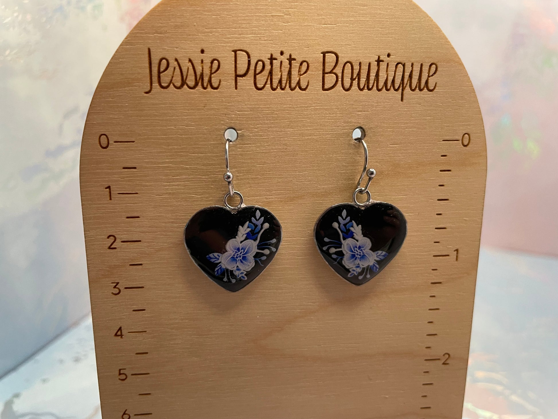 Heart-shaped earrings with floral design on a wooden display card with 'Jessie Petite Boutique' branding.