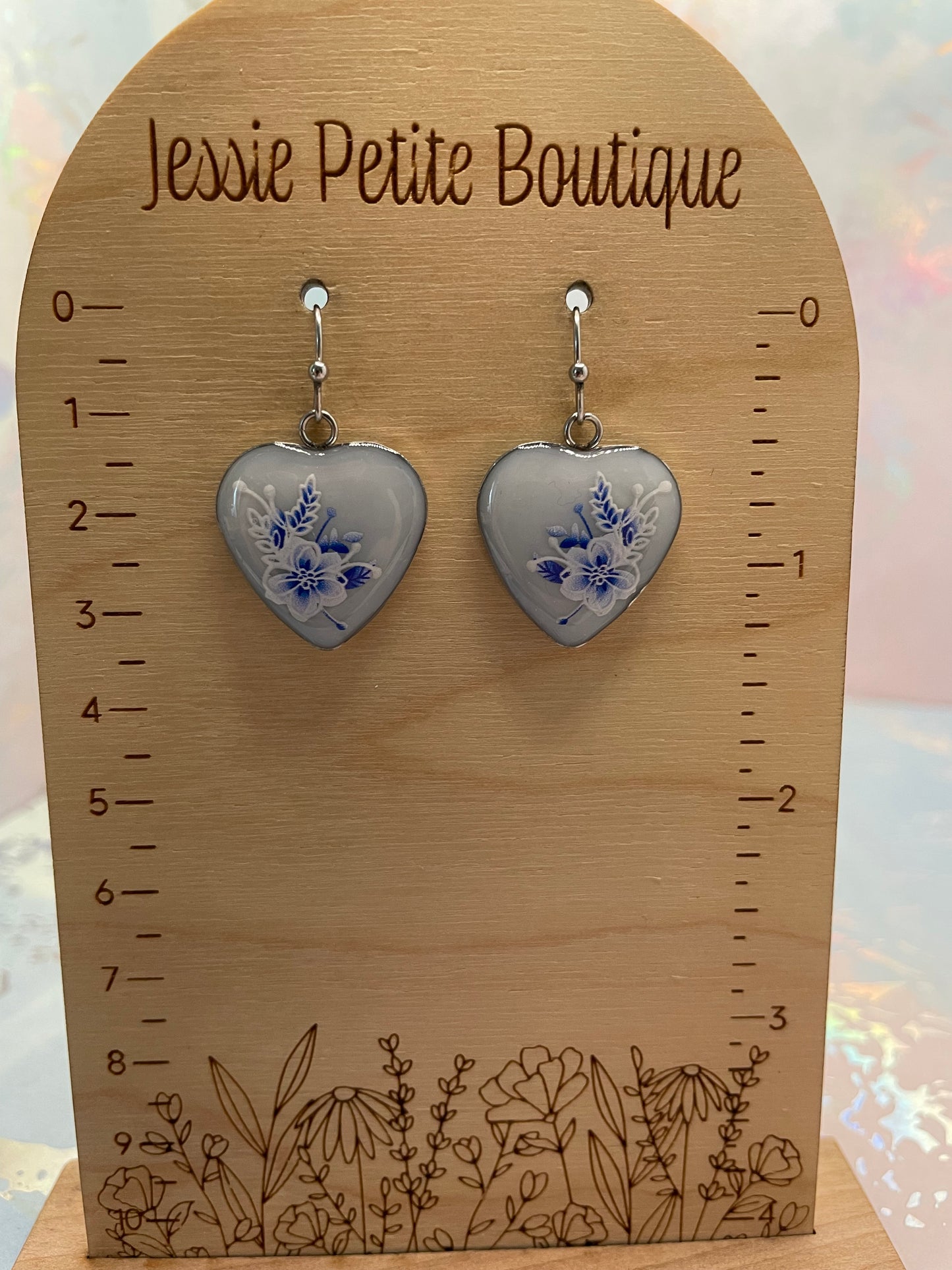 Heart-shaped earrings with floral design on a wooden card with measurements, branded 'Jessie Petite Boutique'.