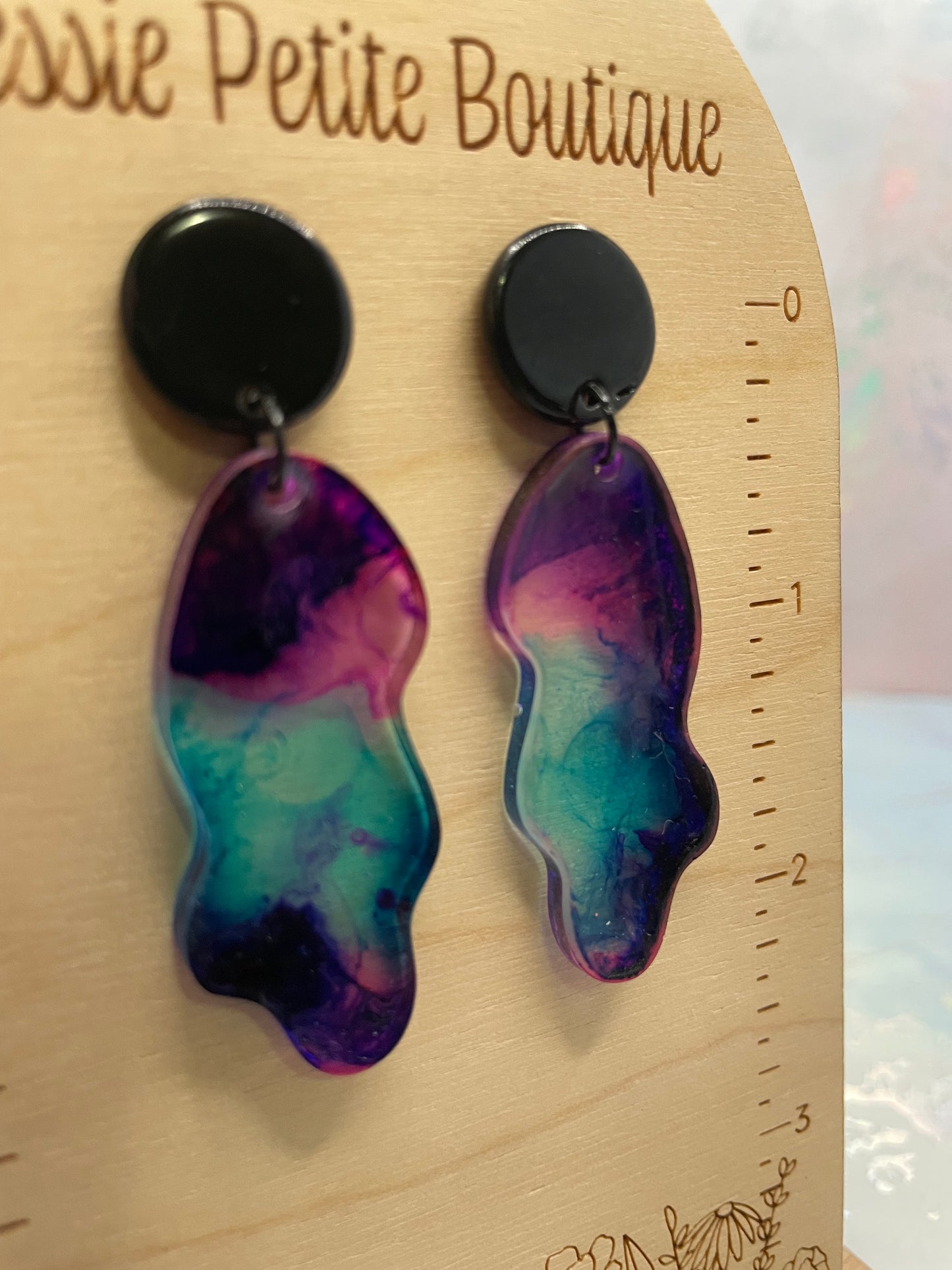 Colorful earrings on a wooden surface with a ruler for scale.