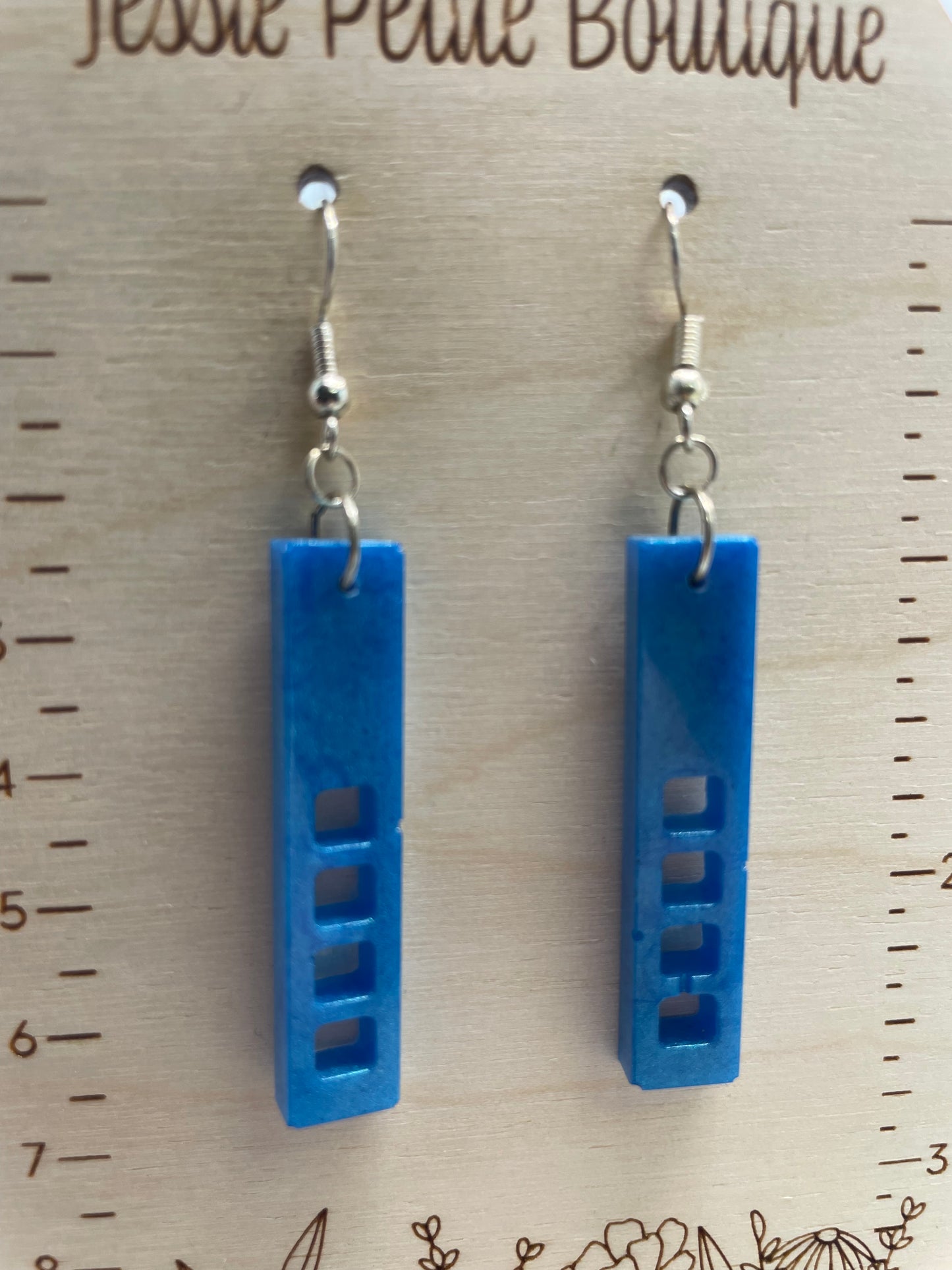 Blue resin earrings on a wooden surface with a ruler for scale.