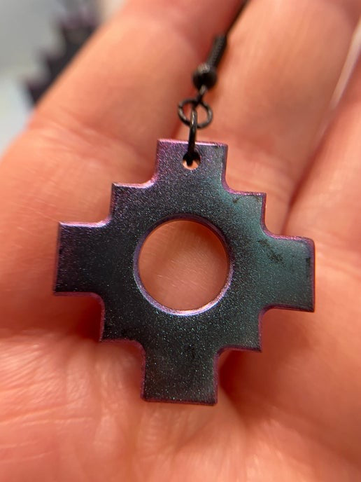 Metallic purple pendant held in a hand