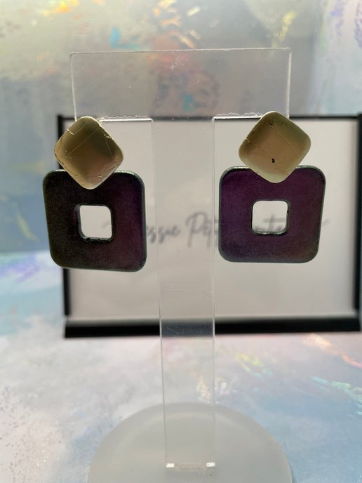 Pair of earrings on a clear stand with a blurred background