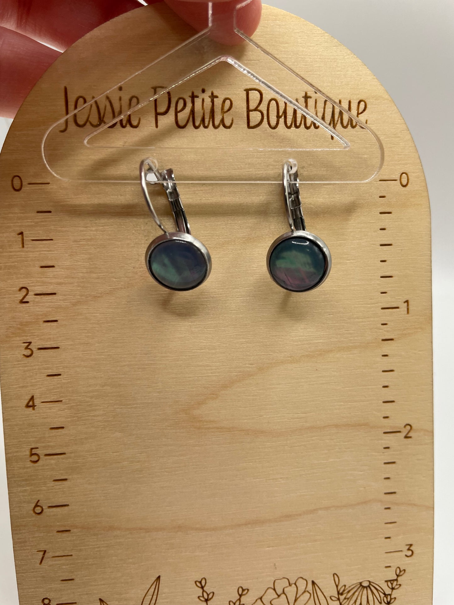 Shell Cabochon Leverback Earrings on a wooden card with measurements, held by a hand.