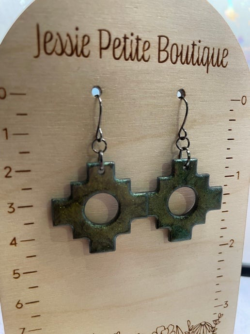 Pair of green metal earrings on a wooden display card with 'Jessie Petite Boutique' branding.