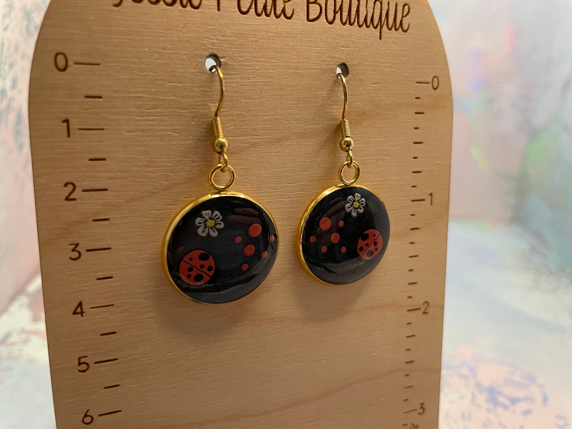 Black earrings with floral designs on a wooden display card.