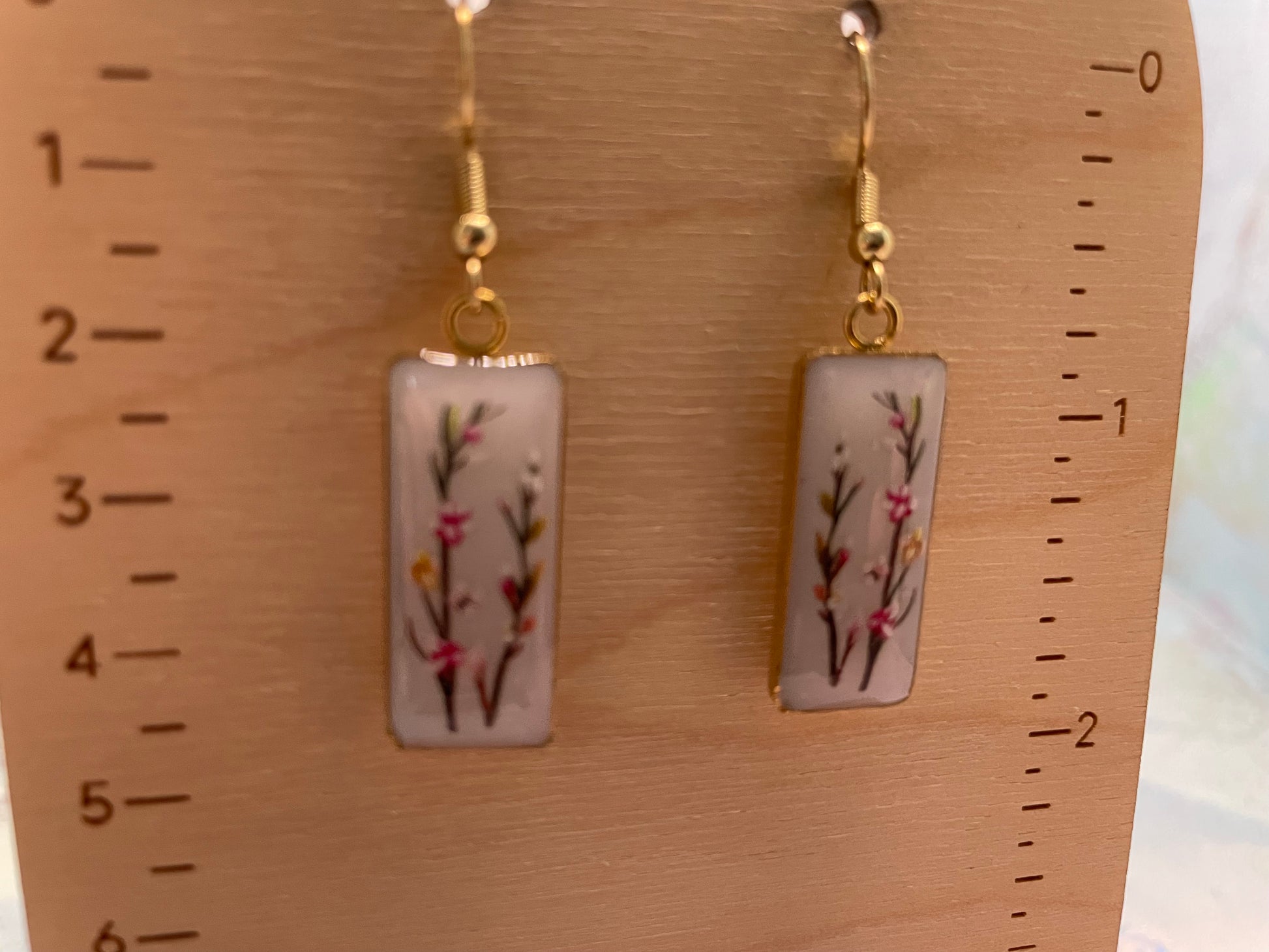 Pair of earrings with floral design on a wooden ruler